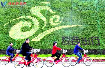 市民騎公共自行車路過市人民廣場一處花壇。記者 張馳